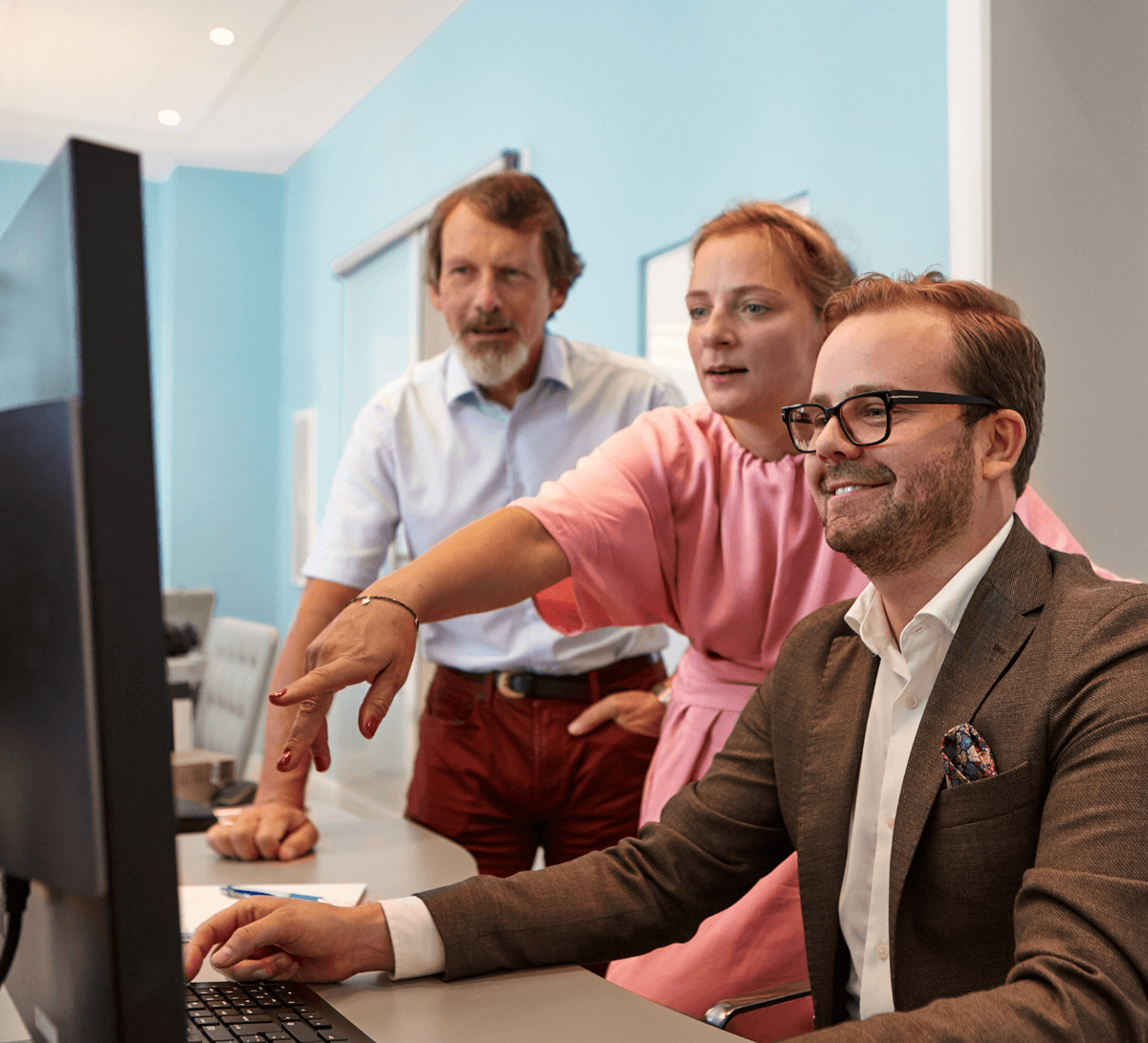 3 people discussing work in front of a computer